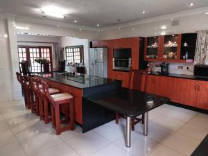 a kitchen with a black counter top and wooden cabinets at Contemporary spacious guesthouse surrounded with green garden and pool in Mount Pleasant - 2063 in Kingsmead