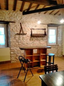 Habitación con pared de piedra, mesa y sillas. en La casa di Mastro Ivetto en Arcevia