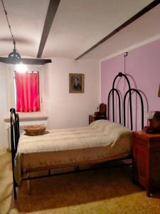 1 dormitorio con cama con marco de metal y ventana en La casa di Mastro Ivetto, en Arcevia