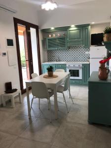 a kitchen with green cabinets and a white table and chairs at BREZZA DI LEVANTE in Cefalù