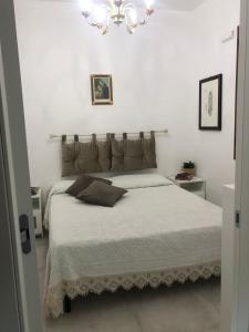 a bedroom with a large bed with white sheets and a chandelier at BREZZA DI LEVANTE in Cefalù