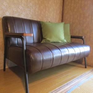 un sofá de cuero marrón sentado en la esquina de una habitación en ゲストハウス杉田 古民家貸切の完全プライベート空間 杉田駅徒歩2分 セルフチェックイン, en Yokohama
