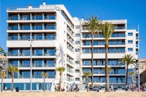 un edificio blanco con palmeras delante en INNSiDE by Meliá Costablanca - Adults recommended, en Benidorm