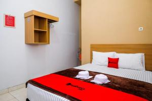 um quarto com uma cama com um cobertor vermelho em RedDoorz Syariah near Perempatan Kartasuro em Surakarta