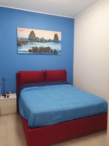 1 dormitorio con cama roja y pared azul en Acitrezza Vacanze Mare, en Aci Castello