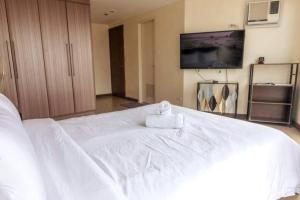 a large white bed with a towel on top of it at Cozy 2-bedroom in The Venice Luxury Residences in Manila