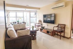 a living room with a couch and a tv at Cozy 2-bedroom in The Venice Luxury Residences in Manila