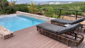 a deck with two chairs and a swimming pool at Luxury studio with private jacuzzi near beaches in Grote Berg +10 photos