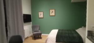 a bedroom with a green wall with a bed and a chair at Le soleil du Revard in Aix-les-Bains