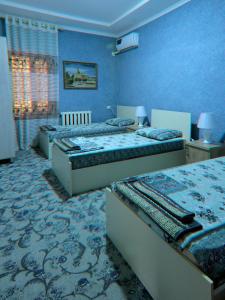 1 dormitorio con 2 camas y paredes azules en LION Guest House en Bukhara
