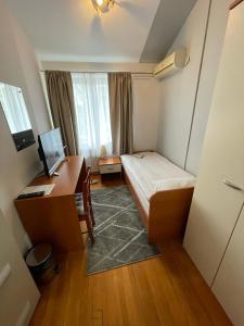 een kleine kamer met een bed en een bureau met een computer bij Perla Inn in Osijek