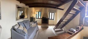 Saturnia Country Loft Montemerano ( Terme a 6 km) في مونتيميرانو: غرفة معيشة مع أريكة ودرج
