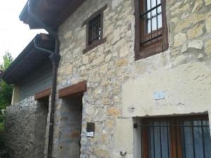 un edificio de piedra con 2 ventanas y una puerta en El horno Albergue Manzanos en Manzanos