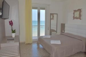 a bedroom with a bed and a balcony with the ocean at Hotel Astoria in Pesaro