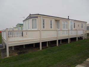 a mobile home on a deck with a porch at The Chase Topaz Super 4 Berth panel heated Wrap around veranda in Ingoldmells
