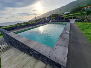 a swimming pool with the ocean in the background at Casas da Prainha B in Santo Amaro