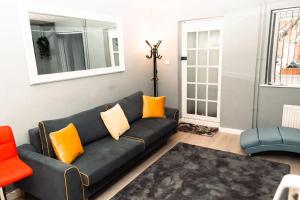 a living room with a black couch and orange pillows at Elegant 2 bed with hot tub and a host of amenities in Liverpool
