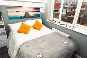 a bedroom with a bed with orange pillows and two windows at Elegant 2 bed with hot tub and a host of amenities in Liverpool