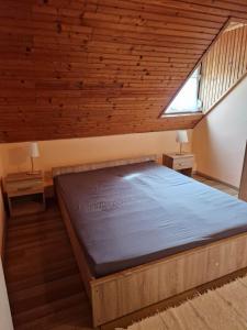 Cama en habitación con techo de madera en Szilasi Vendégház, en Tüskevár