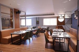 ein Restaurant mit Tischen und Stühlen in einem Zimmer in der Unterkunft Hotel Grand Alleppey in Alappuzha