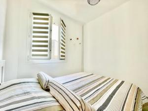 a bed in a white room with a window at U Paradisu - Balcon - 100m mer - Parking - Climatisation in Propriano