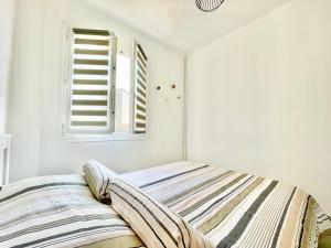 Ce lit se trouve dans un dortoir blanc doté d'une fenêtre. dans l'établissement U Paradisu - Balcon - 100m mer - Parking - Climatisation, à Propriano