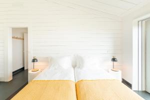 a white bedroom with two beds and two lamps at Casas da Prainha C in Companhia de Baixo