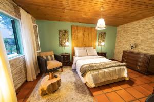 1 dormitorio con 1 cama y 1 silla en PineHouse, en Curral das Freiras