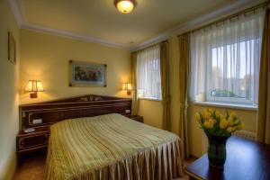塔爾努夫山的住宿－Hotel na Podzamczu，一间卧室,配有一张床,桌子上放着花瓶
