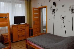 a bedroom with a bed and a dresser with a television at Willa Cicha in Rabka-Zdrój