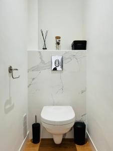 La salle de bains est pourvue de toilettes blanches et de murs en marbre. dans l'établissement Sognu di Matteu - Bel appartement entièrement climatisé - vue mer, vieux port Bastia, à Bastia