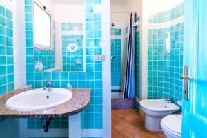 a blue tiled bathroom with a sink and a toilet at Residence Hotel Lu Nibareddu in San Teodoro
