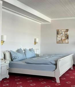 a bedroom with a large bed with blue pillows at Strandhotel Berg in Berg am Starnberger See