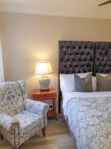 a bedroom with a bed and a chair and a lamp at Elephant Country Guest House in The Crags