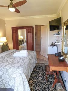 a bedroom with a bed and a desk and a mirror at Elephant Country Guest House in The Crags