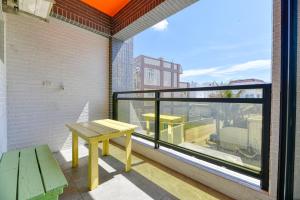 einen Balkon mit einem Holztisch und einem großen Fenster in der Unterkunft 心悅民宿 in Hsing-wen