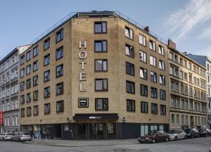 een groot bakstenen gebouw op een straat met geparkeerde auto's bij NYCE Hotel Hamburg City in Hamburg
