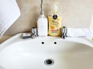 a white sink with a bottle of soap and toothpaste at Mnqobi Lifestyle Apartments in Nelspruit