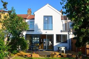 a white house with glass doors and a patio at 5 bedroom sunlit family house with garden in Redbridge