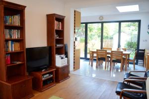 a living room with a television and a dining room at 5 bedroom sunlit family house with garden in Redbridge