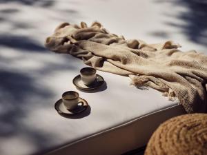 two cups on top of a bed with a blanket at Estelle Villa, a Flamboyant Escape with Pool, By ThinkVilla in Zakynthos Town +33 photos