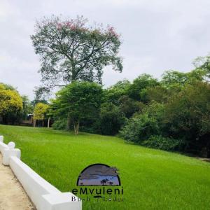 pole zielonej trawy z białym płotem w obiekcie Emvuleni Bush Lodge w mieście Pietermaritzburg