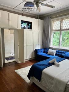 1 dormitorio con cama, sofá y TV en Emvuleni Bush Lodge, en Pietermaritzburg