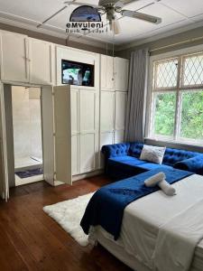 a bedroom with a bed and a couch and a tv at Emvuleni Bush Lodge in Pietermaritzburg