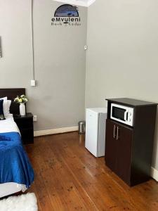 a room with a bed and a microwave on a counter at Emvuleni Bush Lodge in Pietermaritzburg