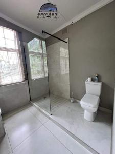 a bathroom with a shower and a toilet in it at Emvuleni Bush Lodge in Pietermaritzburg