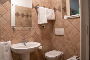 ein Badezimmer mit einem Waschbecken, einem WC und einem Spiegel in der Unterkunft Garnì Centrale in Roncone