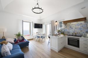 een woonkamer met een blauwe bank en een keuken bij Casa Madonna del Mare in Praiano