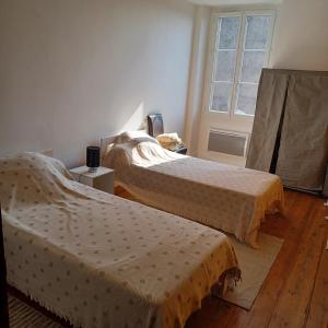 2 Betten in einem Zimmer mit Fenster in der Unterkunft Maison de village entre estuaire et océan in Saint-Yzans-de-Médoc