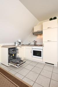 a kitchen with white cabinets and a dishwasher at Apartment Typ C im DG, Haus Friedeburg, Carolinensiel in Wittmund